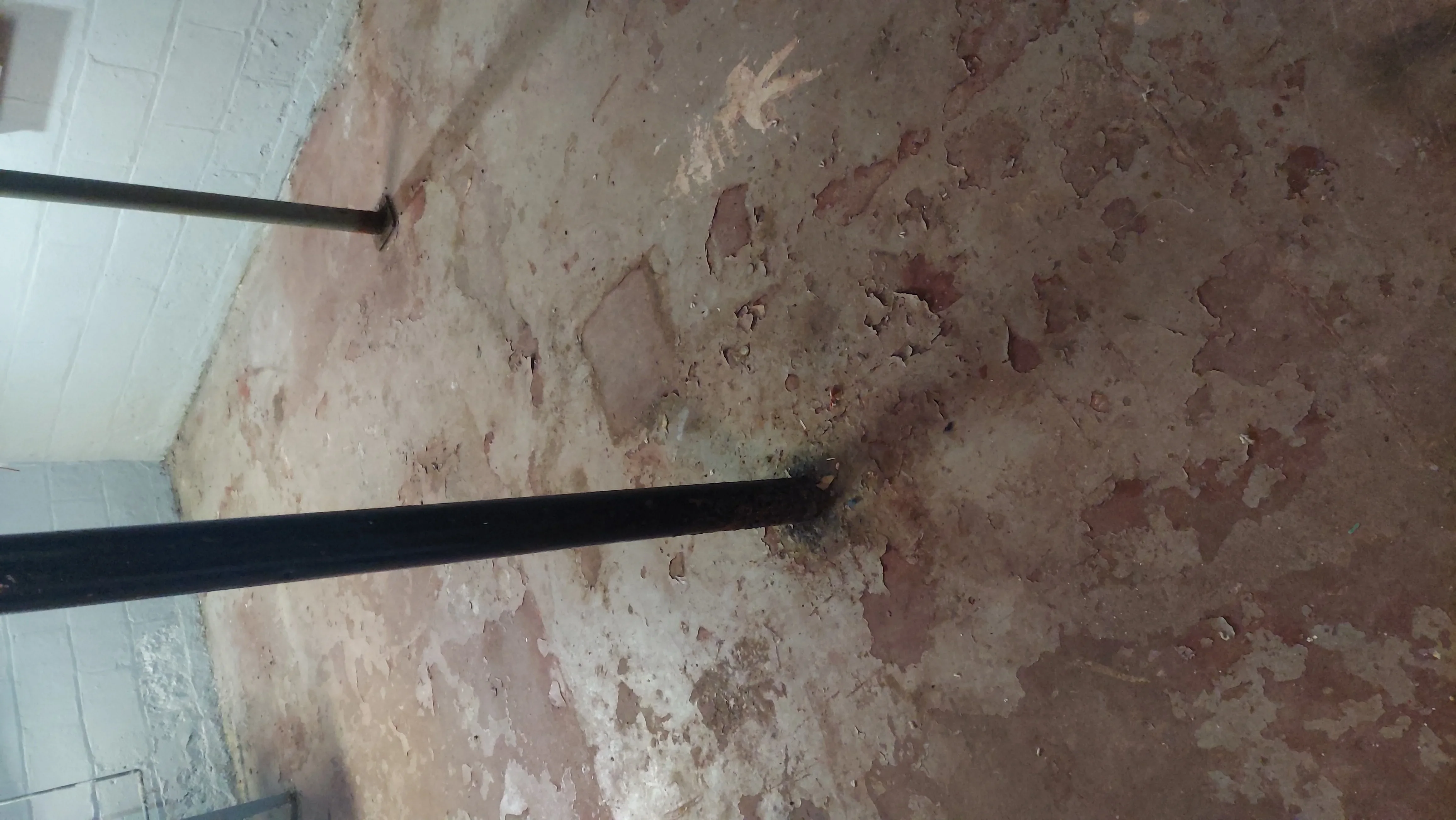 Exposed brick wall with removed plaster and black steel support beam during interior demolition