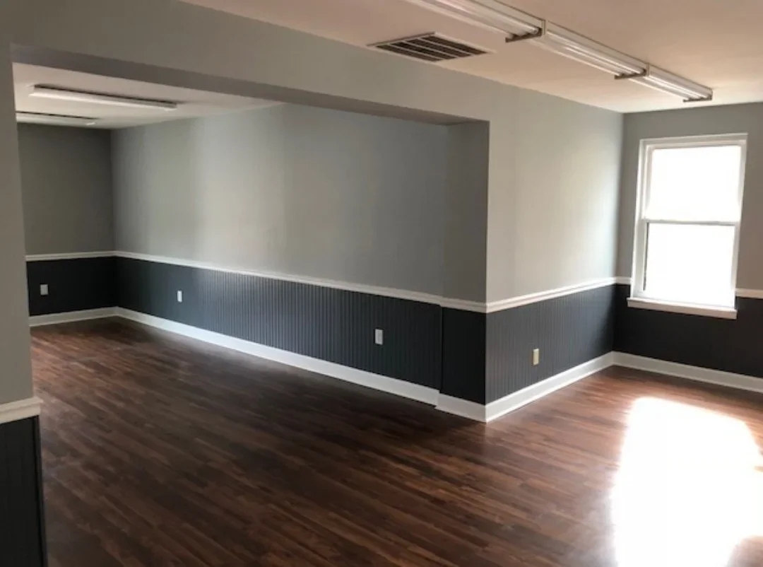 Commercial space with two-tone painted walls, black wainscoting, hardwood flooring, and recessed lighting