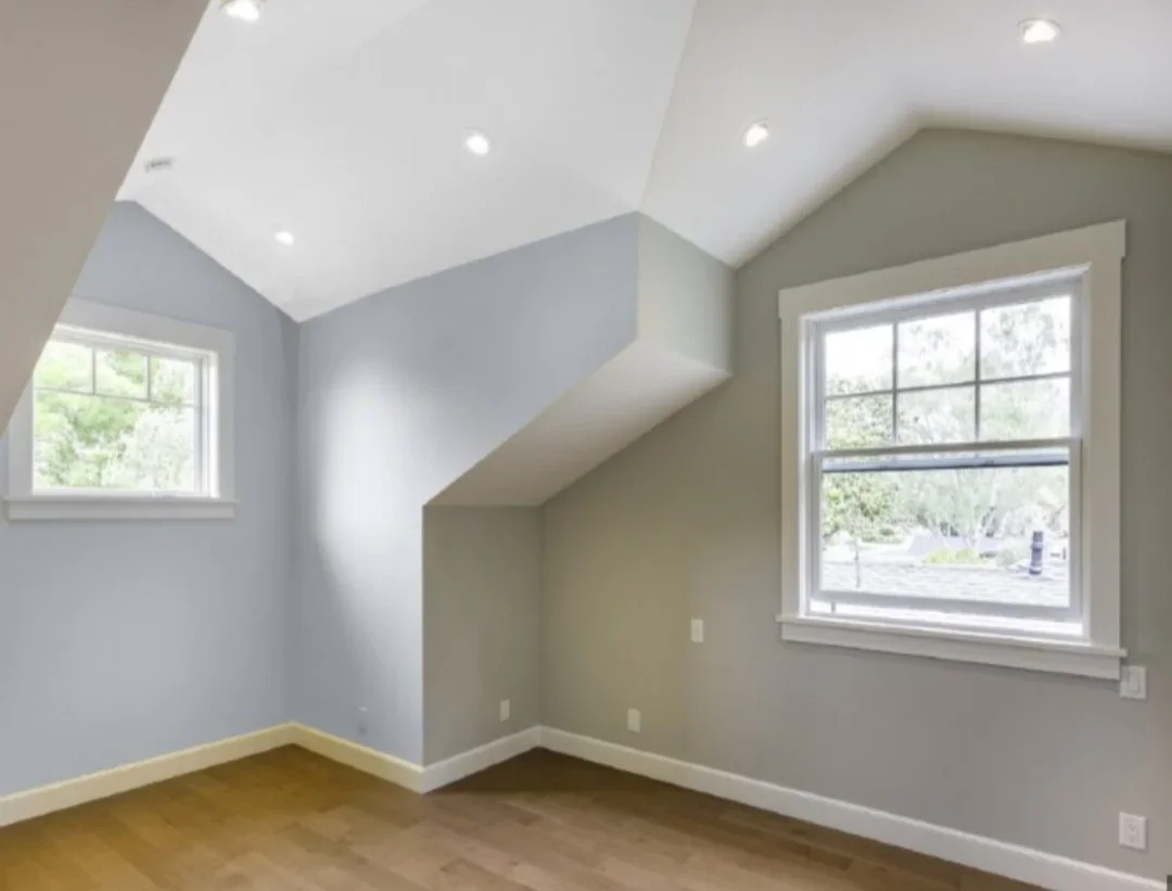 Finished attic bedroom with vaulted ceiling, recessed lights, painted walls, hardwood floor, and new windows
