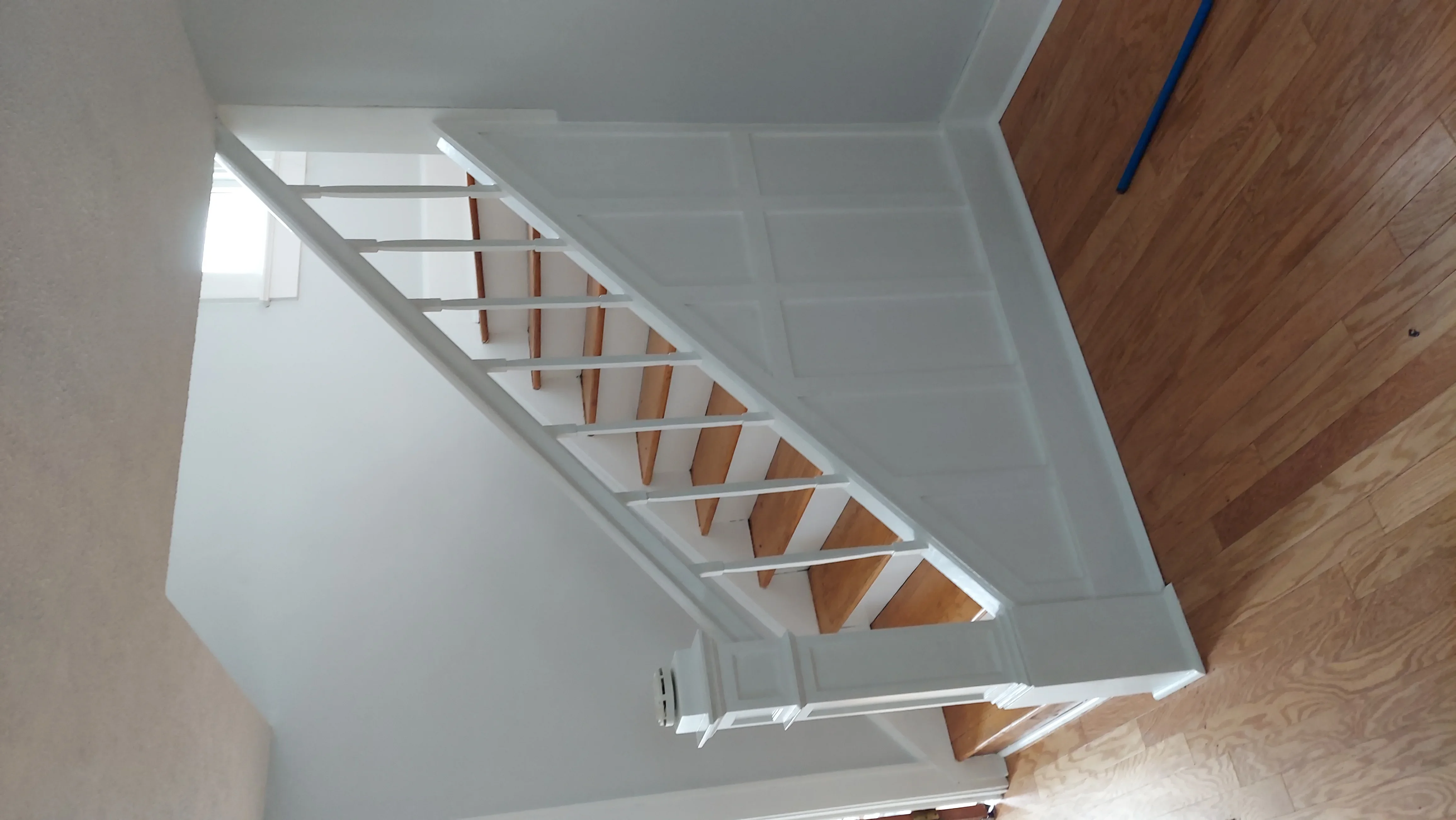 White drywall ceiling and walls with wooden stair framing and support brackets