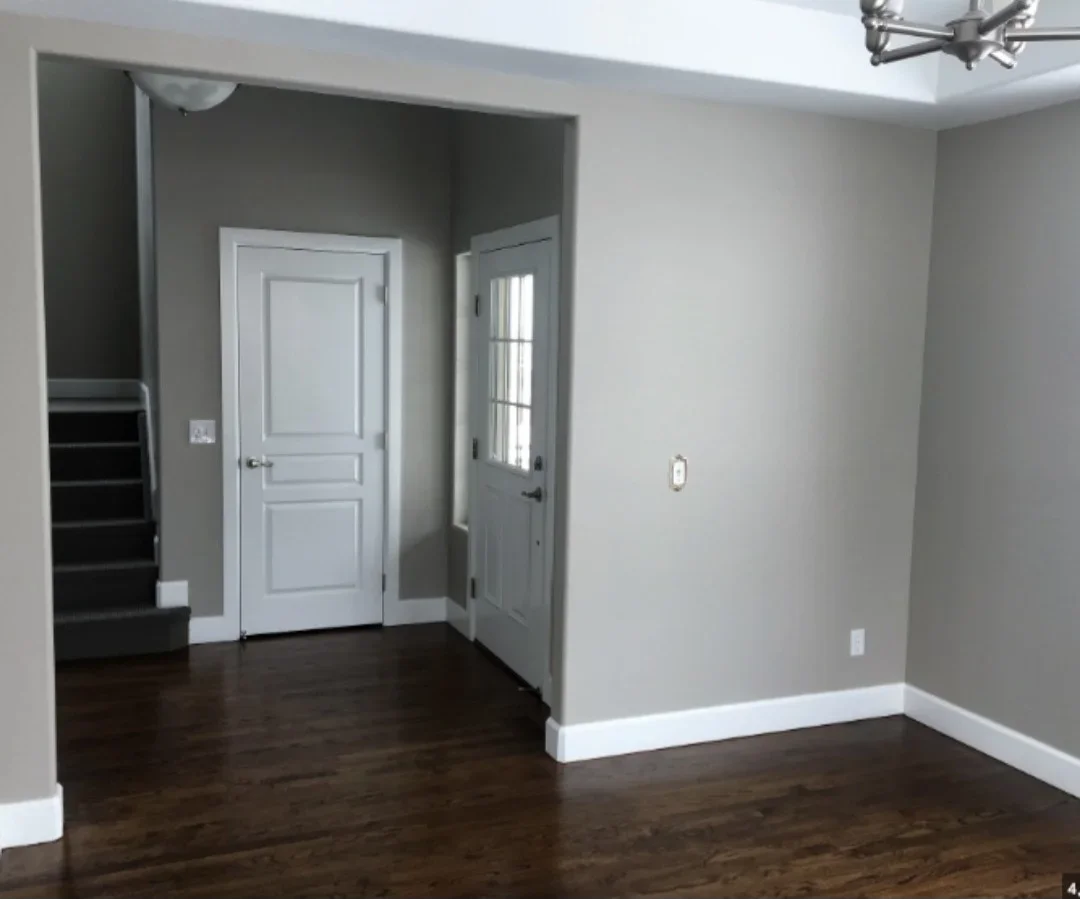 Interior room with gray walls, white trim, dark hardwood floors, and white panel doors