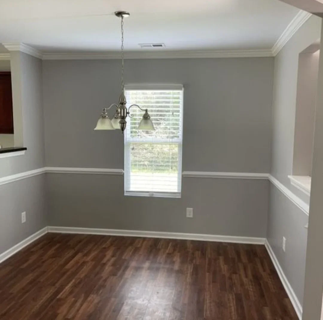 Dining room with gray walls, white trim, hardwood flooring, and pendant lighting