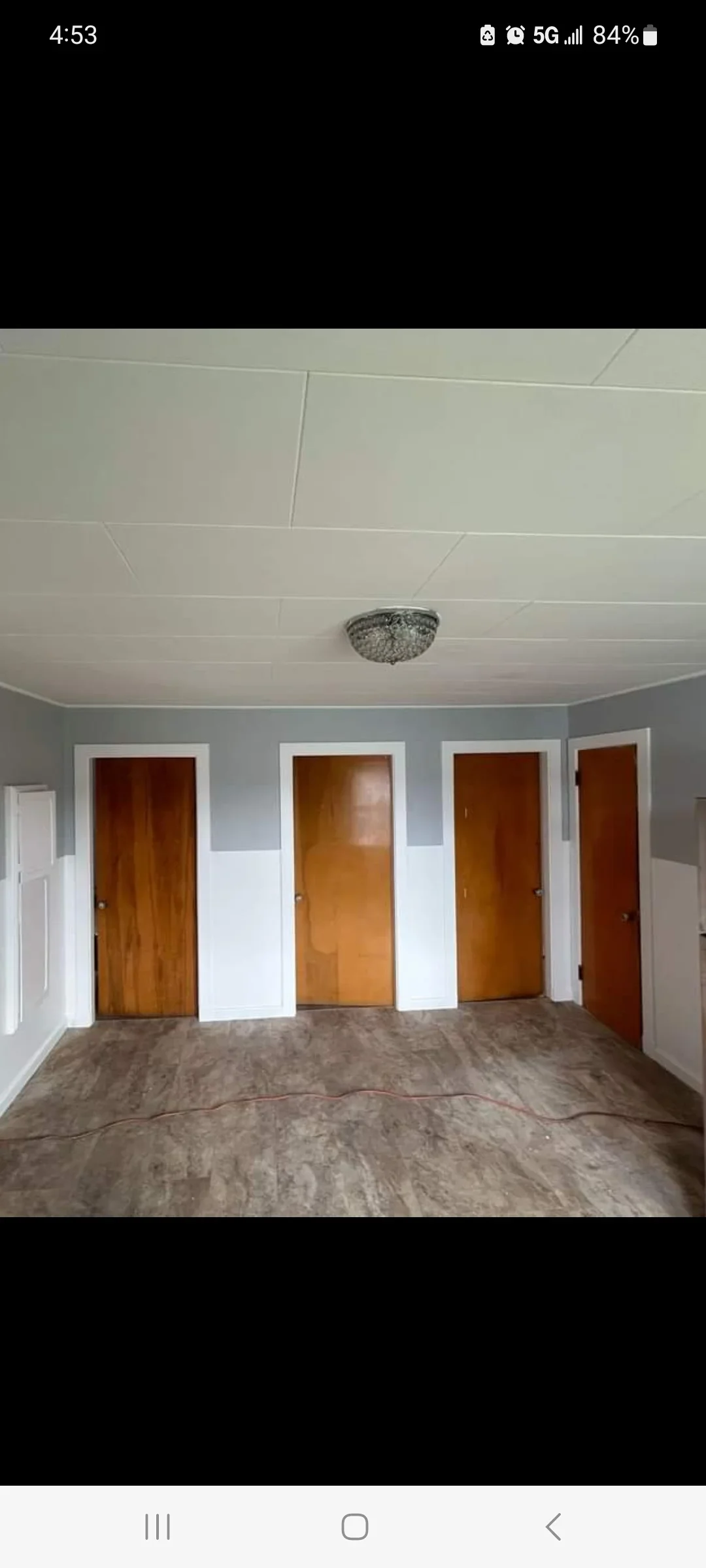 Interior room with new drywall, gray paint, four wood doors with white trim, and concrete flooring