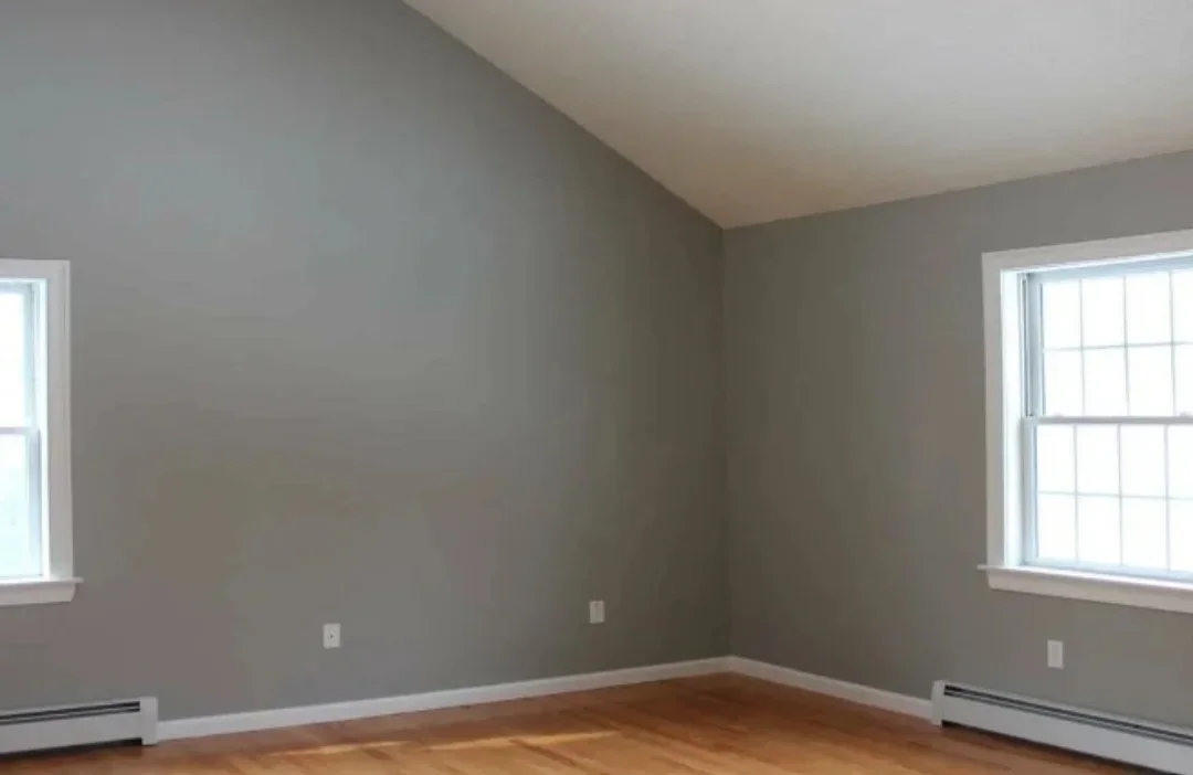 Gray painted walls, smooth ceiling, hardwood flooring, white trim and baseboards, two windows